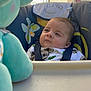 baby, background, blue, child, closeup, clothing, curious, expression, face, high_chair, infant, outdoor, portrait, safety_strap, seat, soft_toy, stuffed_animal, sunlight, toy, wall