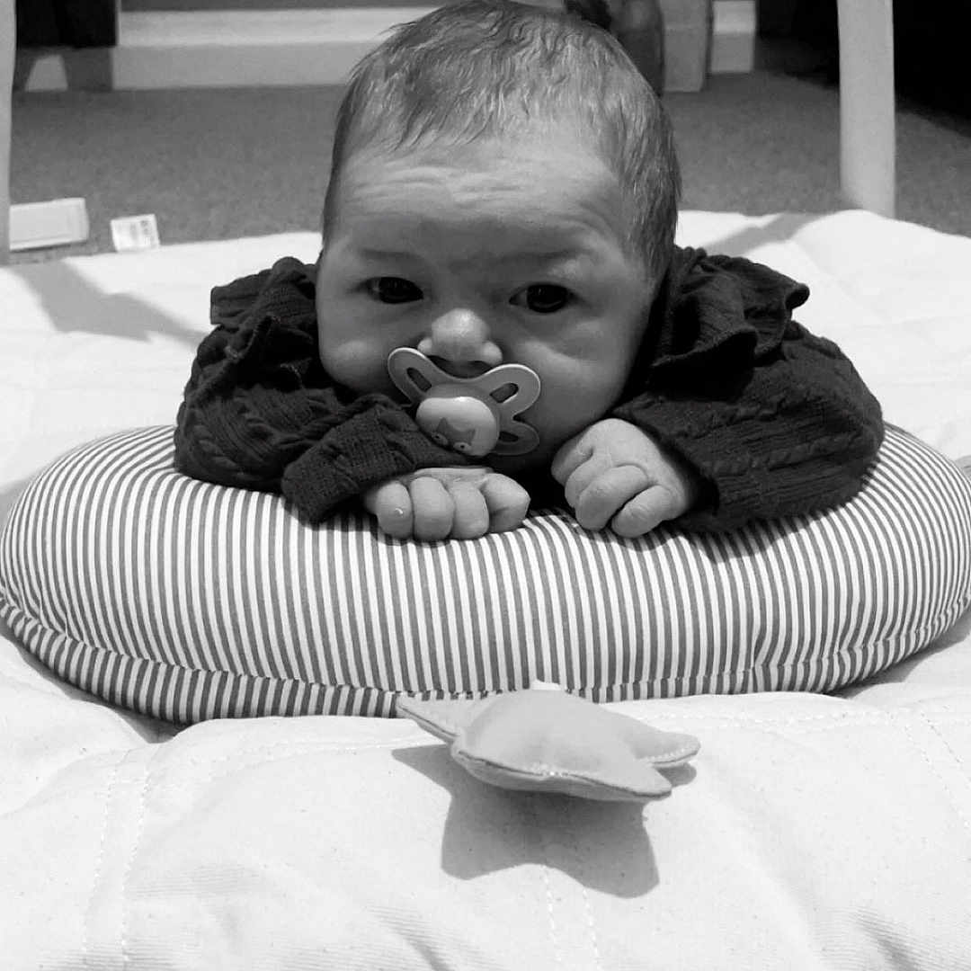 Cecelia-Nevaeh is registered to the contest to win money with this photo: baby, black_and_white, blanket, carpet, child, clothing, cushion, cute, face, floor, hands, head, indoors, infant, lying_down, pacifier, radiator, room, soft_toys, striped