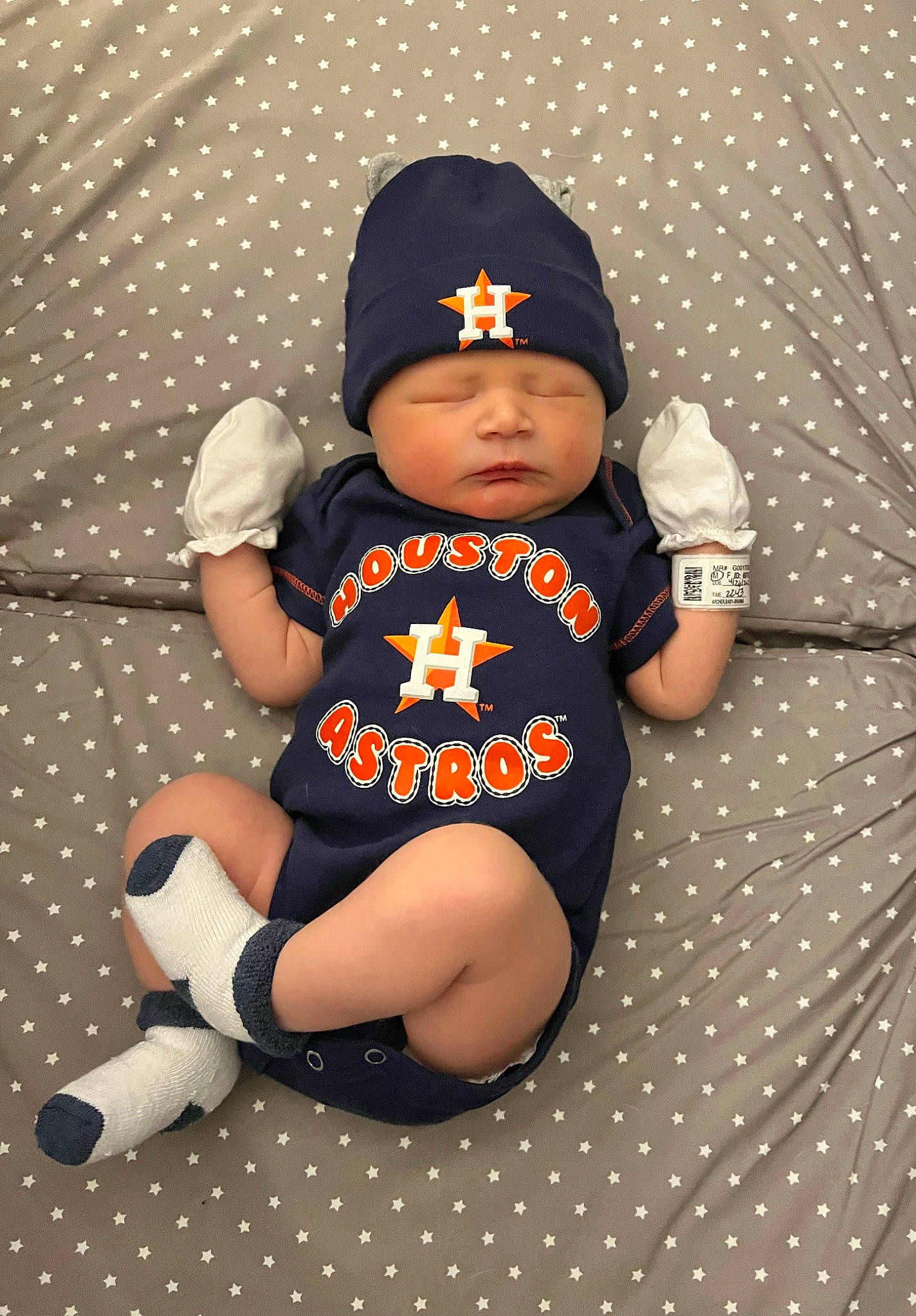 Eddie is registered to the contest to win money with this photo: baby, baby_products, baby_toddler_clothing, baseball_cap, beanie, cap, carmine, child, comfort, costume_hat, fashion_accessory, foot, headwear, human_leg, knee, pattern, person, sitting, sleeve, sock