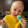 Bryer is registered to the contest to win money with this photo: baby, cabinet, candid, child, close_up, family, happy, high_chair, home, indoors, infant, kitchen, plant, plate, portrait, smiling, table, teething_toy, toy, yellow_bib