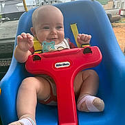 Bryer joined the competition — help win amazing prizes! baby, child, swing, blue_swing, red_safety_bar, smiling, happy, outdoor, toy, playtime, infant, seat, clothing, sock, pacifier, yellow_strap, face, person, daylight, nature