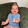 Nora joined the competition — help win amazing prizes! baby, child, smiling, sitting, blue_shirt, floral_diaper, bow, hair, couch, green_couch, corduroy, indoor, person, happy, cute, infant, skin, face, chubby_arms, legs