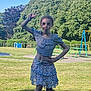 blue_sky, bracelet, casual_clothing, child, crop_top, footwear, girl, grass, nature, outdoor, park, peace_sign, playground, pose, skirt, smile, summer, sunny, trees, young_person