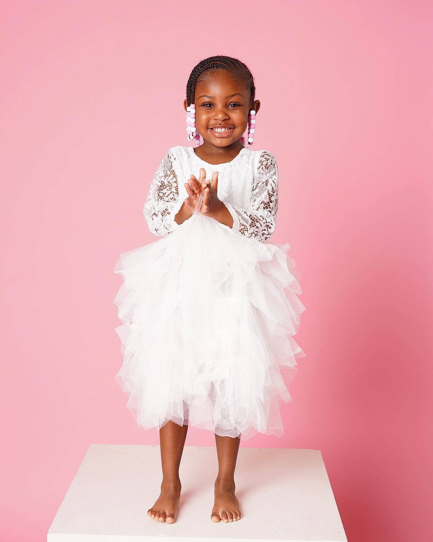 Elysia is registered to the contest to win money with this photo: arm, baby_toddler_clothing, day_dress, dress, embellishment, face, fashion_design, gesture, hair, happy, human_body, joy, leg, neck, one_piece_garment, person, pink, ruffle, sleeve, smile