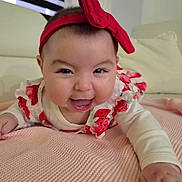 Anastasia is registered to the contest to win money with this photo: baby, headband, red_bow, blanket, smiling, face, infant, cute, happy, indoor, clothing, person, skin, closeup, child, toddler, soft_texture, pink, white, lying_down