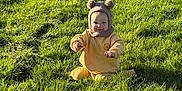 Grayson is registered to the contest to win money with this photo: baby, child, grass, outdoor, sunlight, hat, knit_hat, yellow_clothing, cute, happy, smiling, nature, greenery, sitting, infant, young_child, playful, portrait, person, daytime