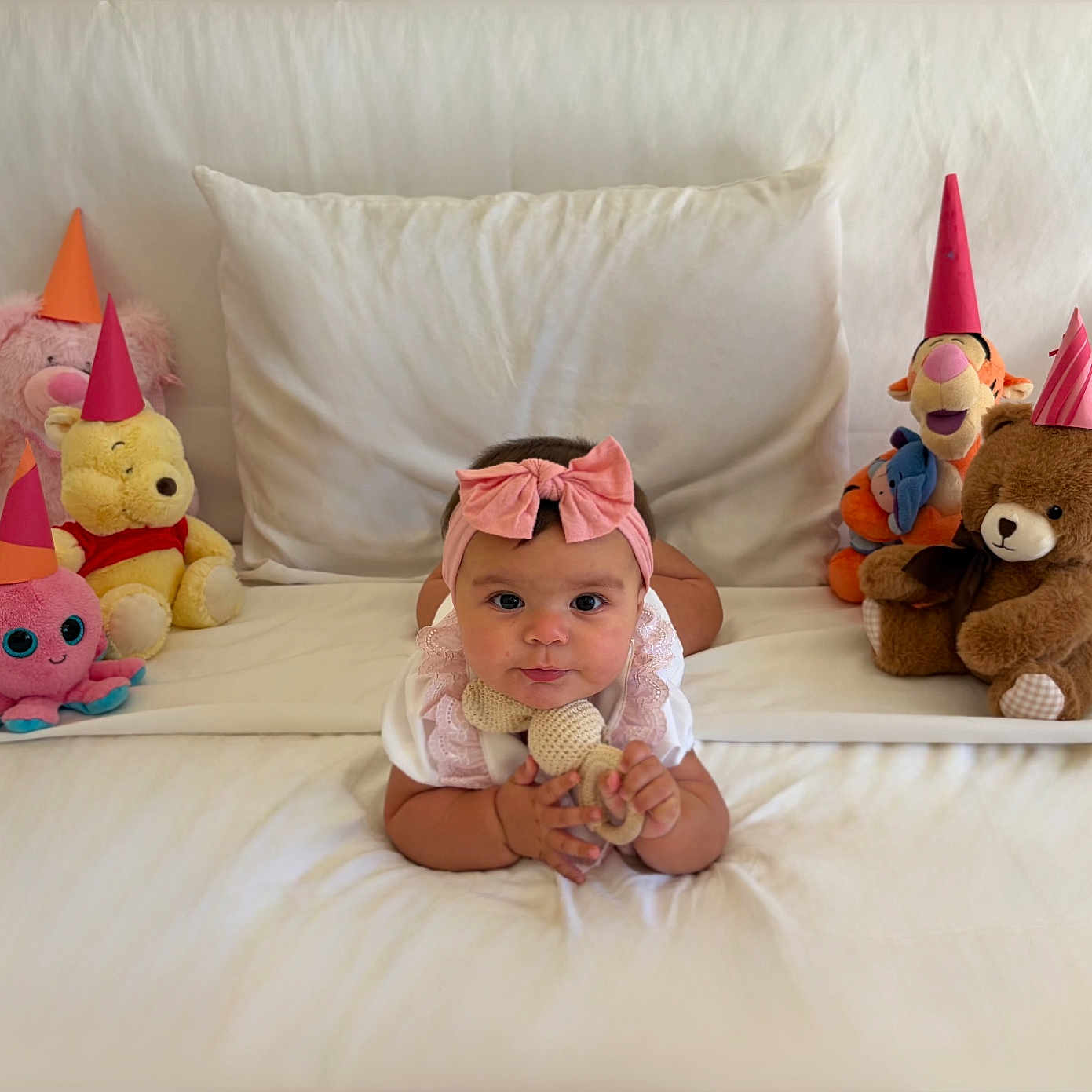 Valentina joined the competition — help win amazing prizes! baby, infant, pink_bow, white_bed, stuffed_animals, party_hats, teddy_bear, octopus_toy, winnie_the_pooh, tigger, plush_toys, cute, indoors, child, smiling, toy, soft_toys, celebration, laying_down, colorful
