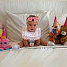 Valentina is registered to the contest to win money with this photo: baby, child, pink_headband, bow, bib, white_bed, stuffed_animals, party_hats, teddy_bear, octopus_toy, tigger_toy, sitting, cute, celebration, indoor, soft_toys, portrait, infant, smiling, home