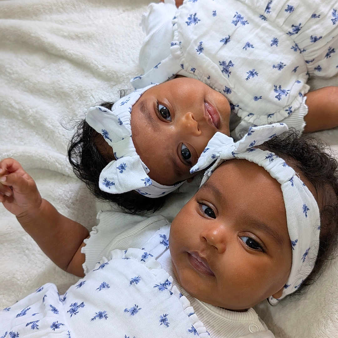 Rufta And Melawit joined the competition — help win amazing prizes! baby, baby_fashion, blanket, bow, child, closeup, cute, floral_pattern, happy, headband, indoor, infant, lying_down, matching_outfits, person, portrait, smiling, soft_texture, two_babies, white_clothing