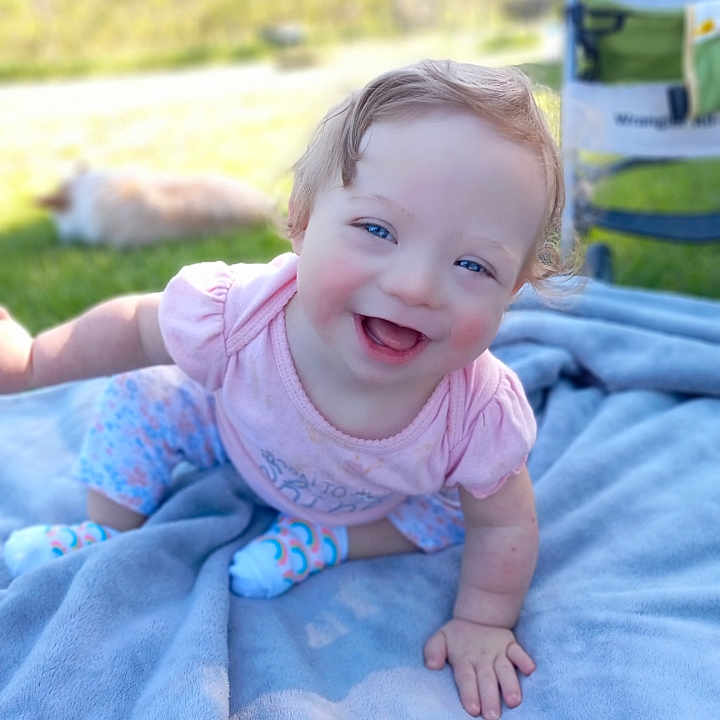 Lydia joined the competition — help win amazing prizes! baby, babylaughing, blanket, bodypart, clothing, crawling, dress, face, grass, happy, head, laughing, pants, person, photography, plant, portrait, quilt, sitting, smile