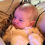 Jarrett is registered to the contest to win money with this photo: baby, infant, mittens, quilt, onesie, face, head, cheeks, eyes, skin, warm_lighting, soft_texture, sleepwear, newborn, cuddly, portrait, cozy, indoors, sleepy, cute