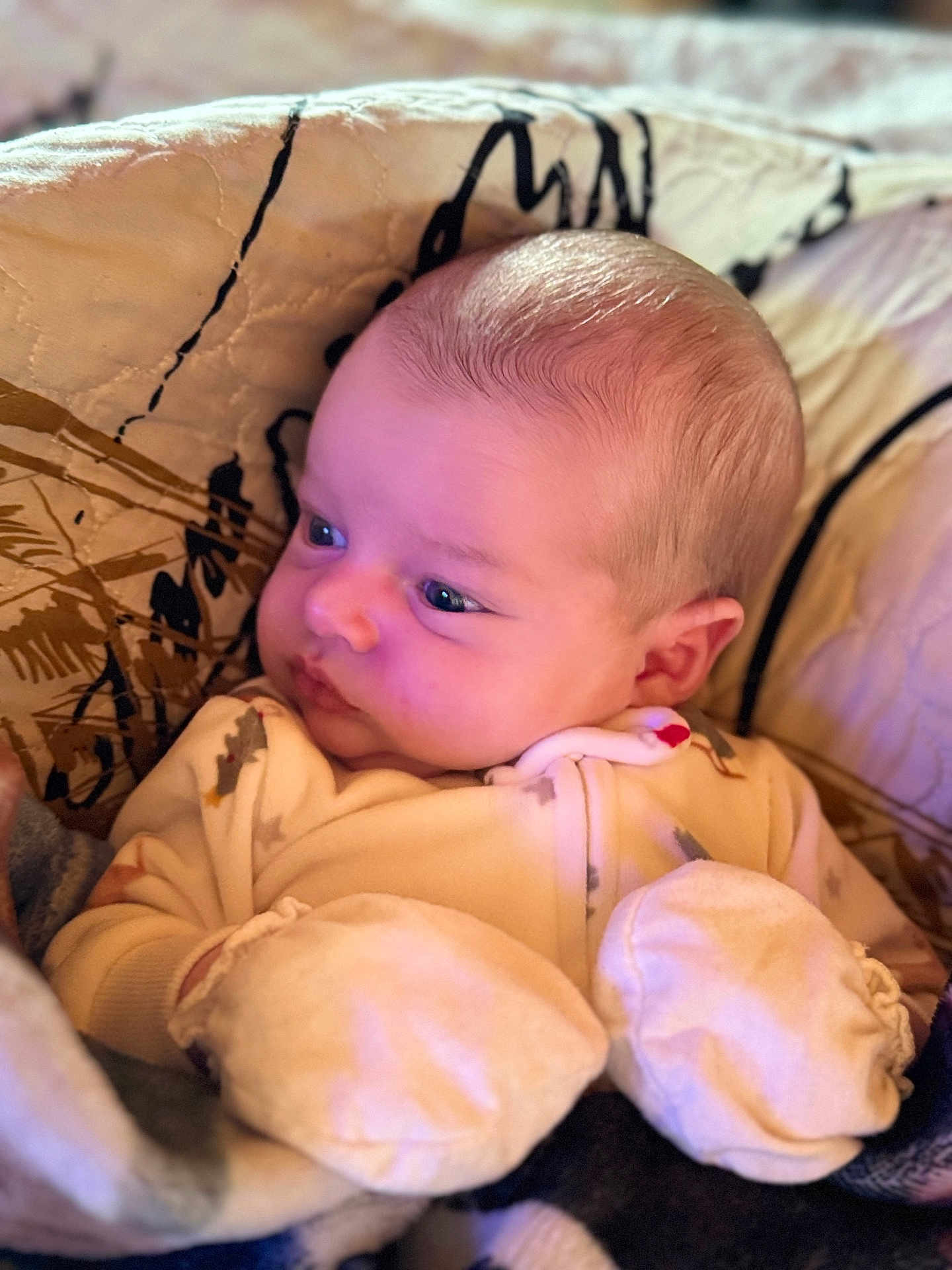 Jarrett is registered to the contest to win money with this photo: baby, infant, mittens, quilt, onesie, face, head, cheeks, eyes, skin, warm_lighting, soft_texture, sleepwear, newborn, cuddly, portrait, cozy, indoors, sleepy, cute