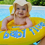 Alice participe au concours pour gagner de l'argent avec cette photo : baby, smiling, inflatable_ring, pool, water, hat, sun_hat, child, outdoor, summer, yellow, blue, green, floating, happy, cute, infant, person, swimming_pool, nature