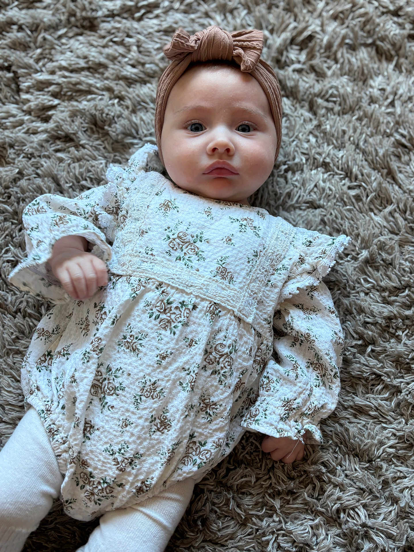 Arliah joined the competition — help win amazing prizes! baby, infant, child, headband, bow, floral_outfit, white_clothing, long_sleeves, lying_down, carpet, rug, texture, cute, portrait, indoors, soft_light, hands, legs, expression, face