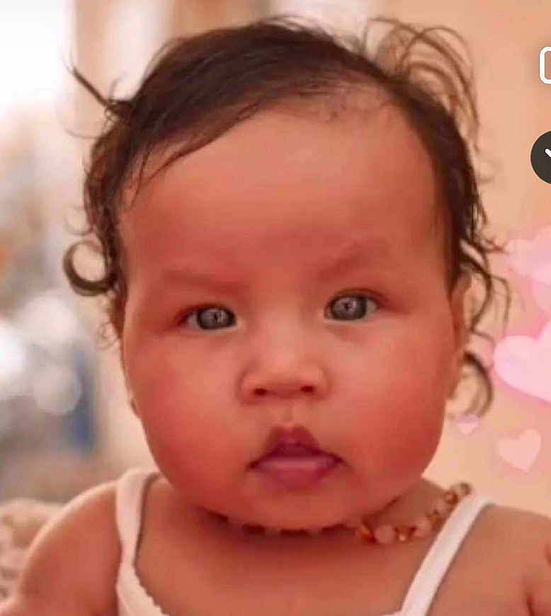 Jasmine participe au concours pour gagner de l'argent avec cette photo : baby, close_up, curly_hair, blue_eyes, necklace, white_tank_top, cute, portrait, face, child, indoor, soft_background, heart_shapes, chubby_cheeks, young_child, infant, skin, expression, person, photography