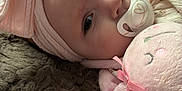 Renesmae joined the competition — help win amazing prizes! baby, infant, pacifier, headband, pink_bow, plush_toy, soft_blanket, hand, face, sleepwear, closeup, cute, child, indoor, resting, portrait, calm, furry, toy, comfort