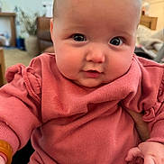 Blythe is registered to the contest to win money with this photo: baby, infant, face, pink_clothing, cute, indoors, person, child, portrait, closeup, chubby_cheeks, sitting, soft_light, curious_expression, young_child, apparel, hand, eyeball, skin, furniture