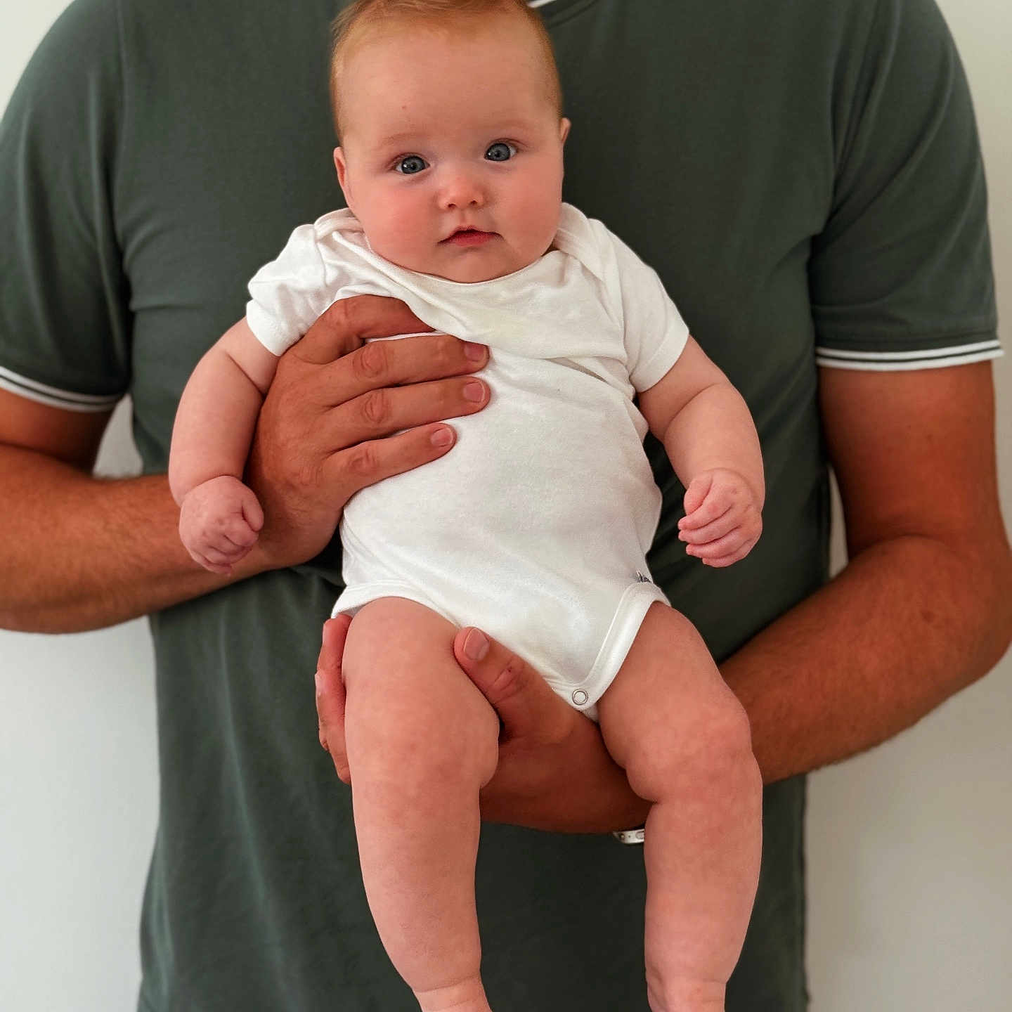 Blythe joined the competition — help win amazing prizes! adult, baby, blue_eyes, casual_clothing, child, cute, face, green_shirt, hands, holding, human, indoor, infant, parent, person, portrait, skin, standing, support, white_onesie