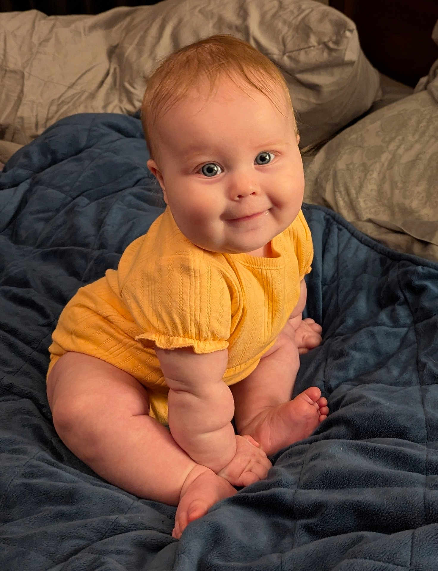 Ayda joined the competition — help win amazing prizes! baby, child, infant, yellow_clothing, smile, blue_blanket, pillow, bed, cute, skin, foot, hand, chubby, sitting, indoors, portrait, happy, plush, young, cozy