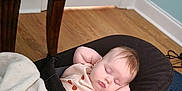 Ayda is registered to the contest to win money with this photo: baby, sleeping, blanket, baby_rocker, wooden_floor, table, door, indoors, child, peaceful, face, infant, clothing, blue_rug, relaxing, home, toddler, nap, cute, resting