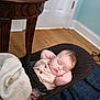 baby, sleeping, blanket, baby_rocker, wooden_floor, table, door, indoors, child, peaceful, face, infant, clothing, blue_rug, relaxing, home, toddler, nap, cute, resting