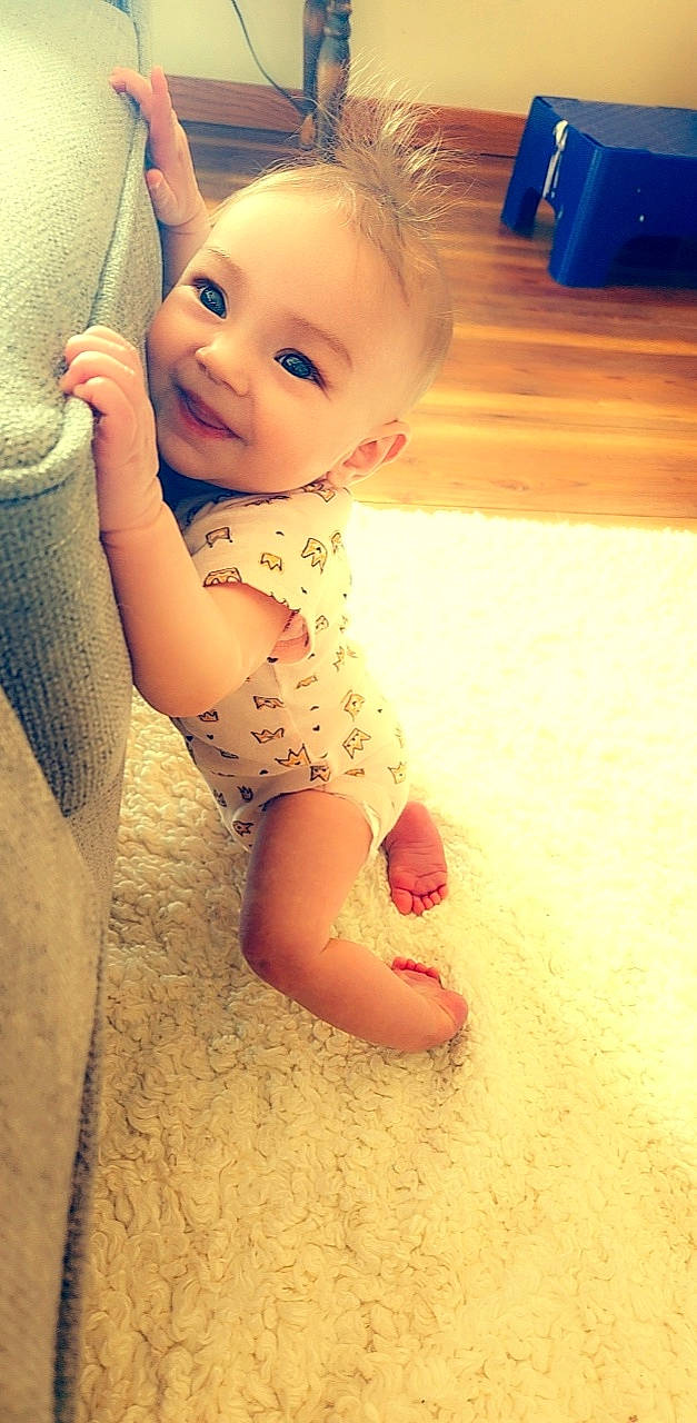 Kinzie is registered to the contest to win money with this photo: baby_toddler_clothing, cheek, chin, eye, face, finger, floor, flooring, hairstyle, happy, head, human_body, iris, leg, lip, mouth, nose, person, skin, smile