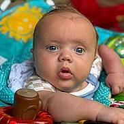Elias joined the competition — help win amazing prizes! baby, infant, face, blue_eyes, arm, toys, playmat, colorful, polka_dots, sun_design, close_up, expression, child, skin, clothing, indoor, cute, person, focus, reaching