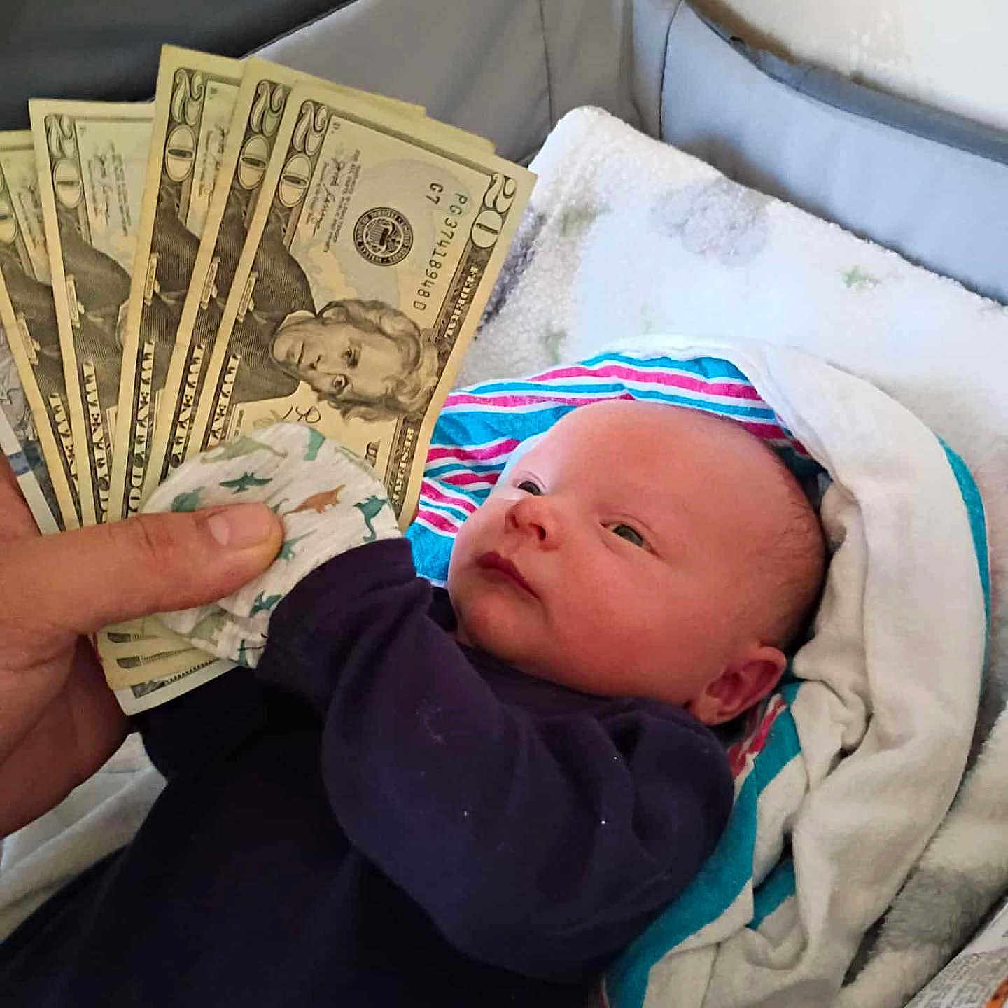 Chase joined the competition — help win amazing prizes! baby, infant, child, face, eyes, portrait, lying_down, blanket, clothing, newborn, indoor, bed, cushion, money, dollar_bills, hand, adult_hand, home, colorful_blanket, photography