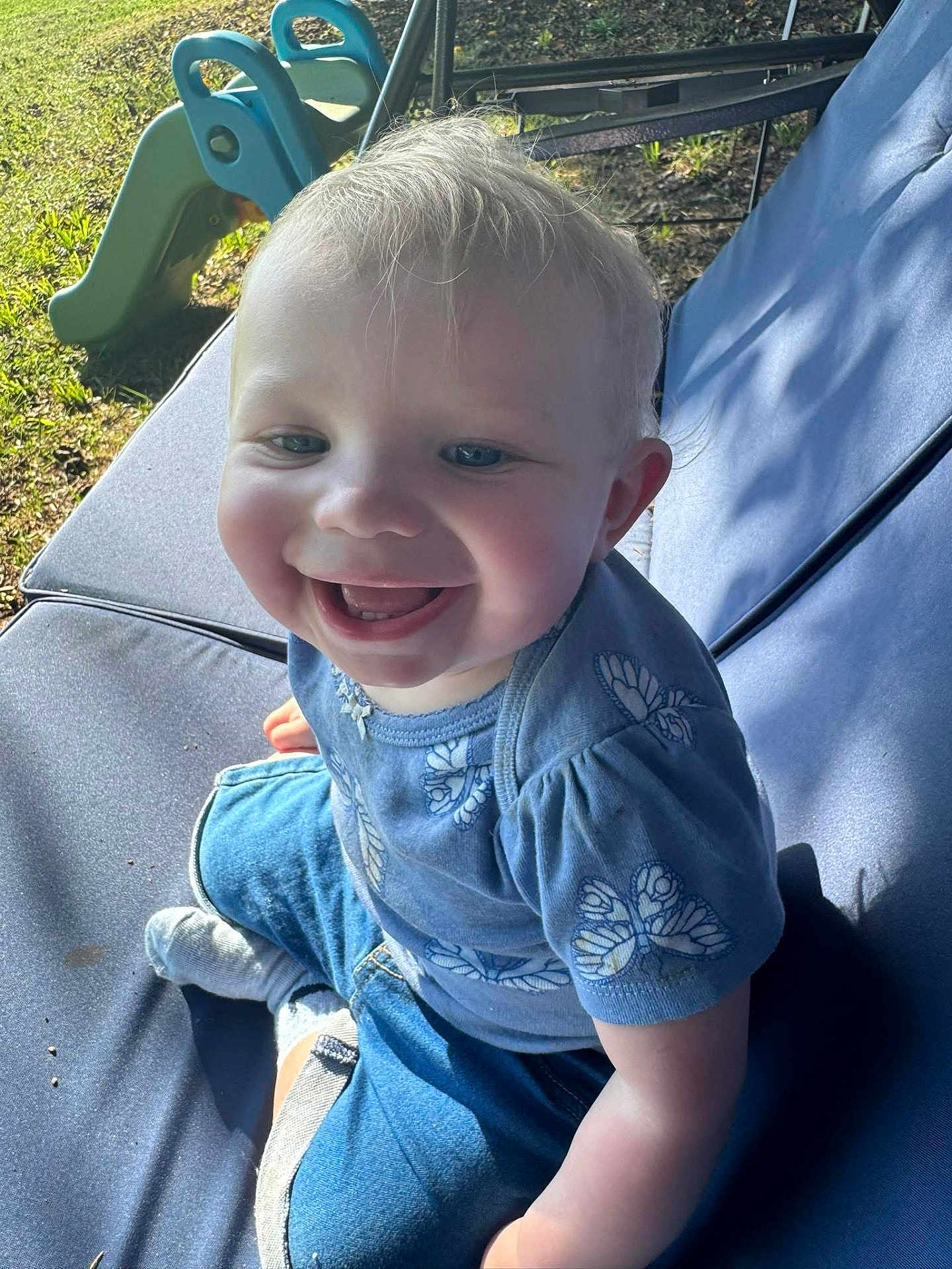 Anastasia joined the competition — help win amazing prizes! toddler, child, smiling, happy, outdoor, sunlight, blue_clothing, shorts, socks, slide, grass, cushion, seat, playing, cute, face, portrait, baby, casual, daylight