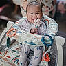 Emma-Rose is registered to the contest to win money with this photo: baby, child, infant, smiling, happy, portrait, sitting, activity_seat, high_chair, teether, toy, rattle, colorful, indoors, home, patterned_clothing, onesie, carpet, playtime, face
