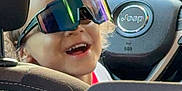 Mateo is registered to the contest to win money with this photo: car, casual, child, curly_hair, daylight, fun, happy, inside, jeep, portrait, reflection, seat, smiling, steering_wheel, sunglasses, sunlight, transportation, vehicle_interior, window, young