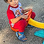 blue_sandals, casual, child, concrete, curly_hair, cute, grass, looking_up, outdoor, pajamas, plastic_toy, play, playtime, red_clothing, sandals, smiling, summer, sunlight, toy_vehicle, young_child