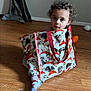 Mateo joined the competition — help win amazing prizes! casual, cat_pattern, child, curious, curly_hair, curtain, decor, face, footwear, home, indoor, light_shadow, person, playful, sitting, sock, tote_bag, toy, wall, wooden_floor