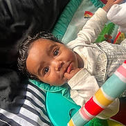 Xion is registered to the contest to win money with this photo: baby, child, infant, face, eyes, hand, blanket, striped, clothing, play_mat, toy, colorful, curly_hair, cute, indoors, portrait, expression, lying_down, soft, comfort