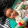 baby, child, infant, face, eyes, hand, blanket, striped, clothing, play_mat, toy, colorful, curly_hair, cute, indoors, portrait, expression, lying_down, soft, comfort