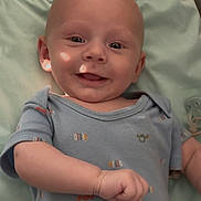 Benjamin is registered to the contest to win money with this photo: baby, infant, smiling, onesie, blanket, pacifier, hand, eyes, bald_head, portrait, indoor, close_up, happy, lying_down, skin, cute, clothing, bed, chubby_cheeks, cheerful