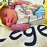 Lavinche Jones is registered to the contest to win money with this photo: baby, blanket, cartoon, child, close_up, colorful, cute, face, indoor, infant, lying_down, newborn, onesie, open_eye, photography, portrait, sleeping_area, soft_blanket, yellow_clothing, yellow_hood