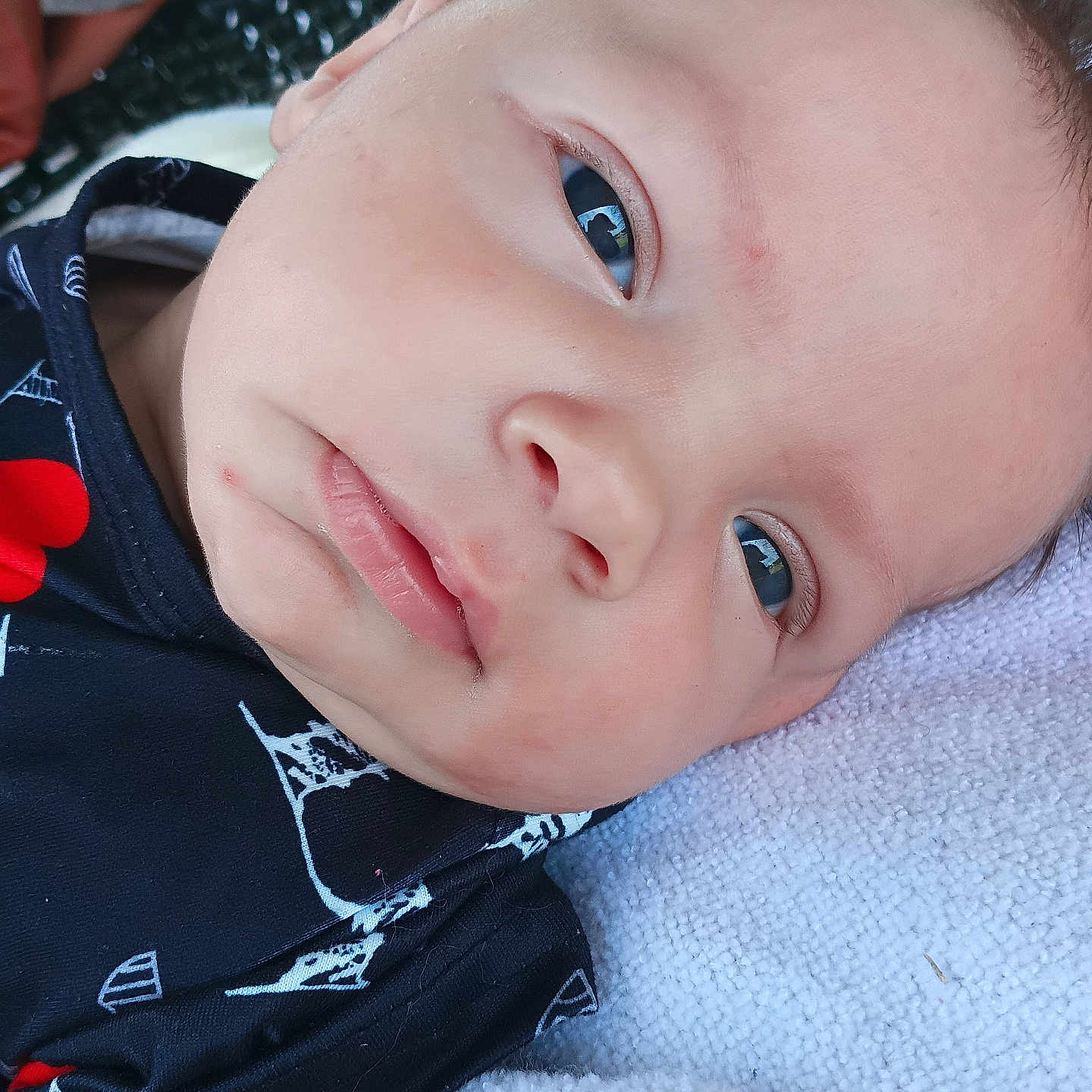 Lavinche Jones is registered to the contest to win money with this photo: baby, blanket, camera, child, close_up, clothing, cozy, eyes, face, hair, happy, head, indoor, infant, lying_down, patterned_shirt, portrait, shirt, skin, smiling