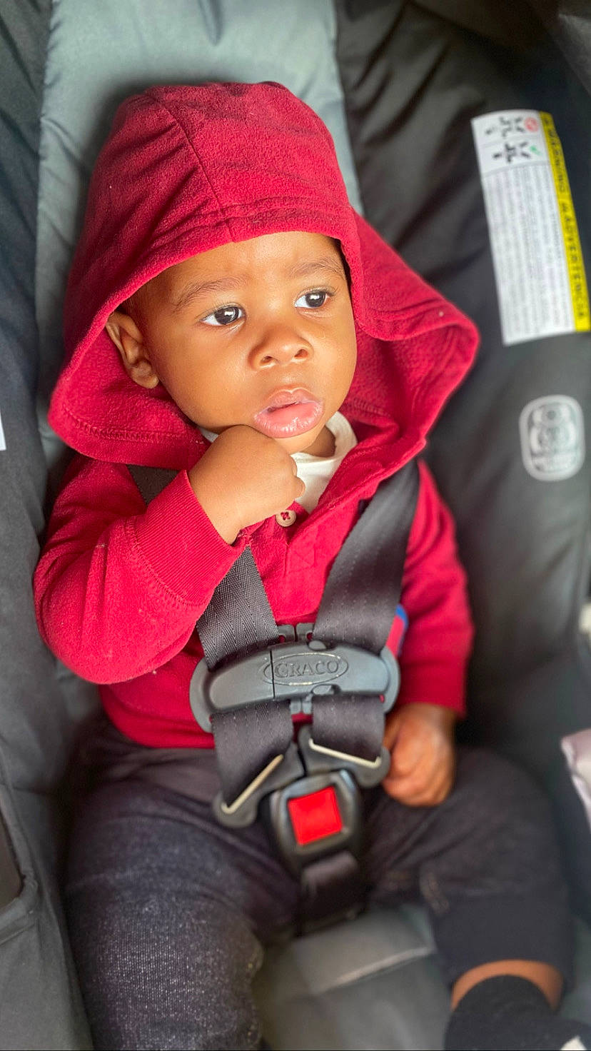 Lawrence joined the competition — help win amazing prizes! baby, baby_carriage, baby_products, baby_toddler_clothing, cap, car_seat, cheek, child, clothing, comfort, finger, headgear, headwear, lip, magenta, nose, person, red, sitting, skin