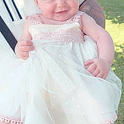 Isabella is registered to the contest to win money with this photo: baby, child, smile, dress, white_dress, lace, outdoor, sunlight, grass, person, holding, cute, happy, footwear, socks, garden, portrait, infant, young_child, human