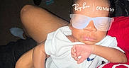 Jah Mauri joined the competition — help win amazing prizes! newborn, baby, infant, sleeping, sunglasses, portrait, close_up, being_held, adult, hands, white_clothing, red_shirt, indoor, dim_lighting, flash_photography, living_room, furniture, bottles, relaxed, fashionable