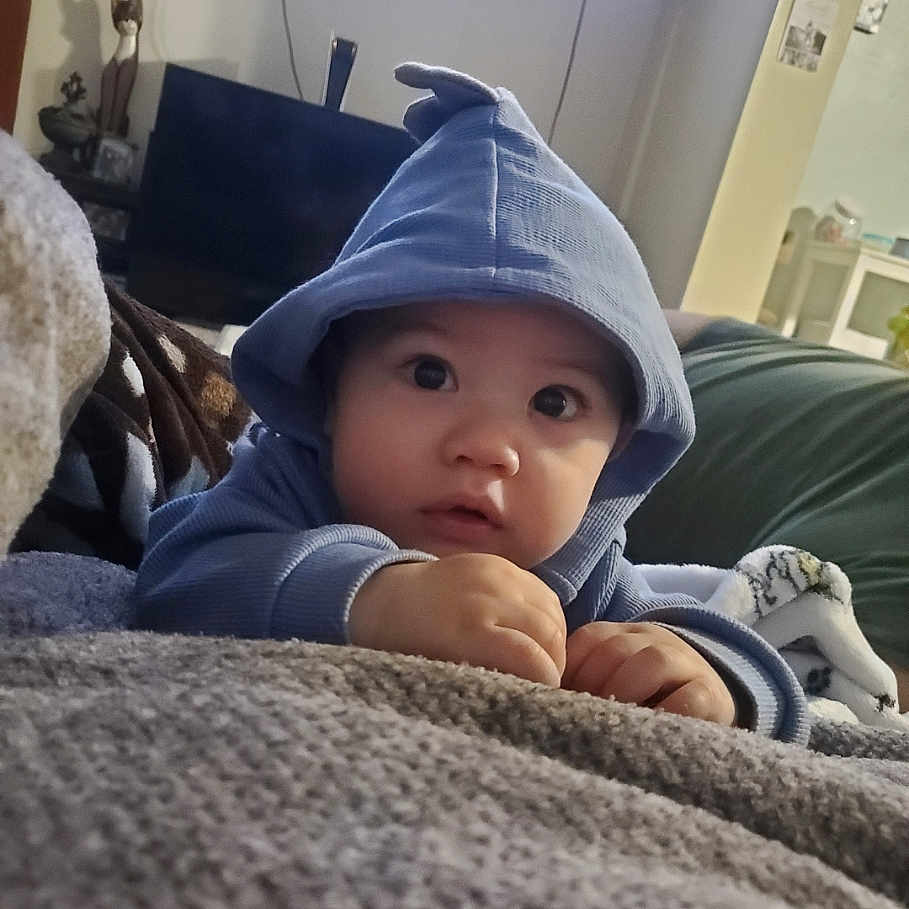 Kenji is registered to the contest to win money with this photo: baby, bodypart, cap, clothing, computerhardware, couch, face, finger, furniture, hand, hat, head, hood, hoodie, knitwear, person, photography, portrait, sweater, sweatshirt