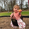 Kimber joined the competition — help win amazing prizes! toddler, child, swing, playground, orange, fruit, outdoor, grass, trees, shoes, socks, pink_clothing, shorts, smile, face, holding, seat, metal_chains, daytime, nature