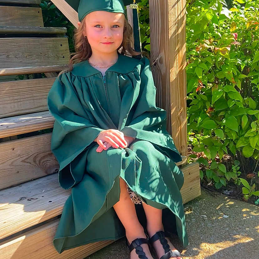 Willow joined the competition — help win amazing prizes! cap, casual, celebration, child, female, graduate, graduation_gown, greenery, happy, nature, outdoor, plants, portrait, shoes, sitting, smiling, steps, sunlight, wood, young