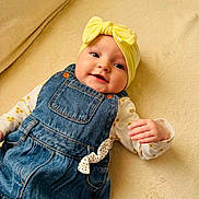 Lyana participe au concours pour gagner de l'argent avec cette photo : baby, infant, child, headband, bow, denim_overalls, onesie, yellow_headband, floral_pattern, blanket, soft_texture, smiling, rosy_cheeks, blue_denim, hand, eyes, cozy, portrait, cute, beige_background
