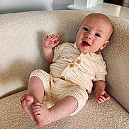 Austen is registered to the contest to win money with this photo: baby, infant, child, knitted_clothing, armchair, cozy, smile, happy, portrait, indoor, cute, comfort, furniture, relaxing, expression, skin, head, feet, hand, button