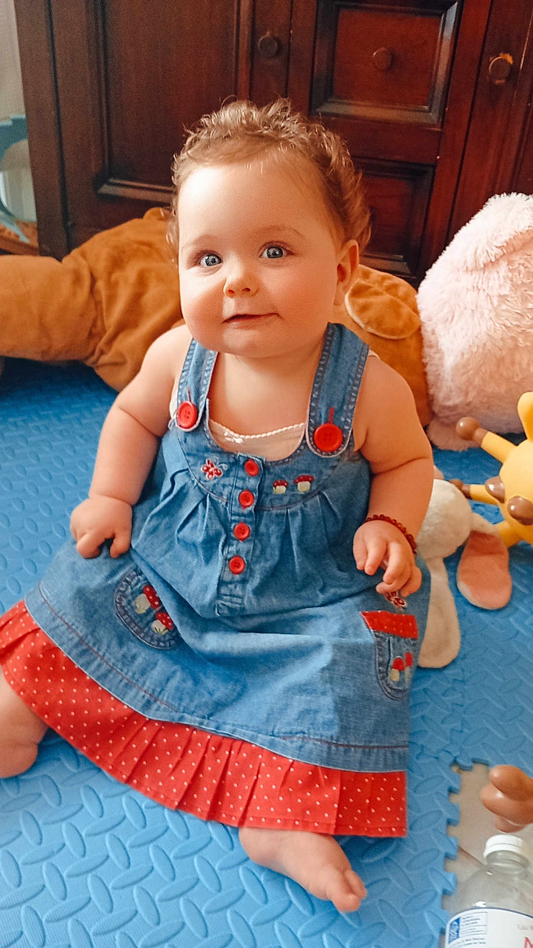 Artemis a rejoint le concours — aidez-le/la à gagner de superbes lots ! baby, barefoot, blue_eyes, bracelet, child, curly_hair, cute, denim_dress, floor_mat, furniture, happy, indoor, plush_toy, polka_dot, portrait, red_buttons, sitting, smiling, toy, wooden_cabinet
