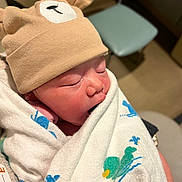 Soren is registered to the contest to win money with this photo: newborn, baby, infant, hat, bear_hat, blanket, animal_print, sleeping, wrapped, hospital, furniture, chair, person, cute, soft_light, closeup, indoors, skin, peaceful, child