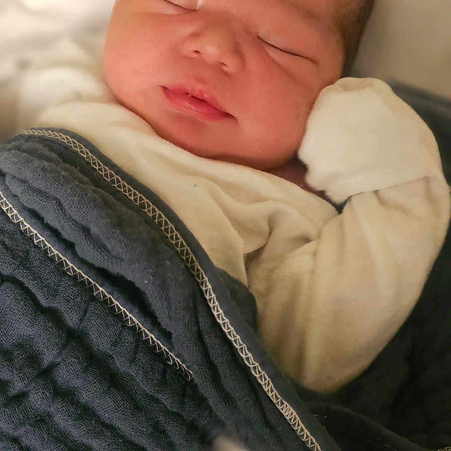 Lucas is registered to the contest to win money with this photo: baby, bed, blanket, clothing, cushion, face, furniture, glove, head, homedecor, knitwear, newborn, pants, person, photography, portrait, sleeping, sweater, towel