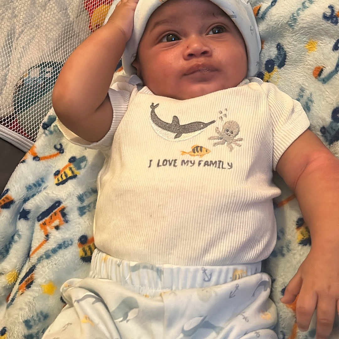 Rahzi is registered to the contest to win money with this photo: baby, bed, bedroom, blanket, cap, clothing, crib, face, furniture, hat, head, homedecor, indoors, infantbed, newborn, person, photography, portrait, quilt, room